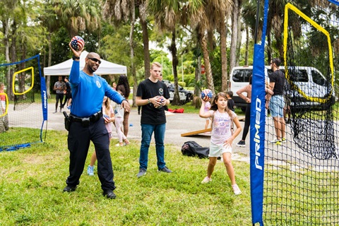Teens towering a ball with police officer into a net.