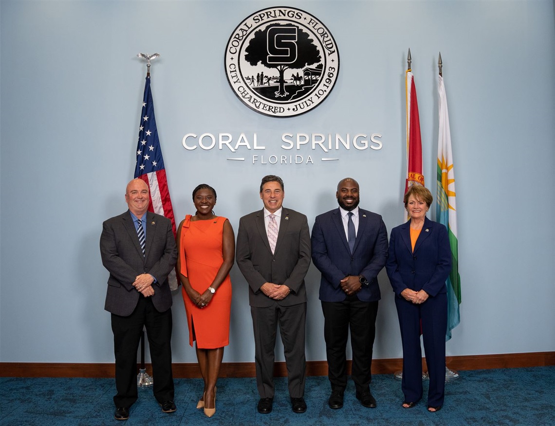 Commissioners formal photo standing in front of city and USA flags - Shawn Cerra, Nancy Metayer Bowen, Mayor Scott Brook, Josh Simmons, Joy Carter